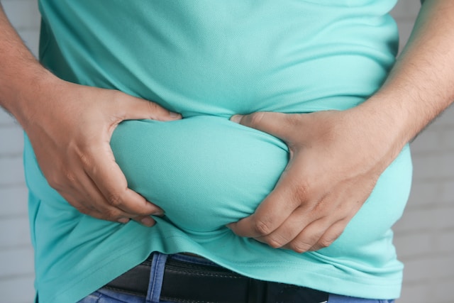 Obese person gripping their belly fat