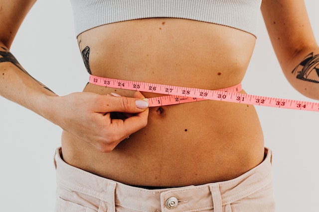 Woman measuring her waist after losing weight